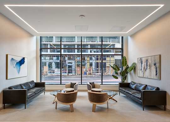 a living room with leather couches and chairs and a large window