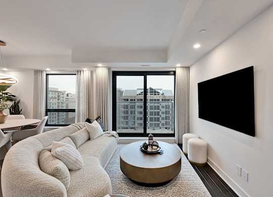 A modern living room with a large window and a flat screen TV mounted on the wall.
