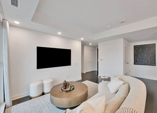A modern living room with a large couch and a flat screen TV mounted on the wall.
