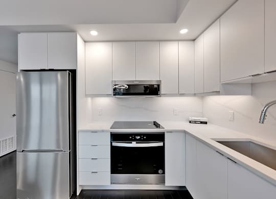 A modern kitchen with white cabinets and stainless steel appliances.