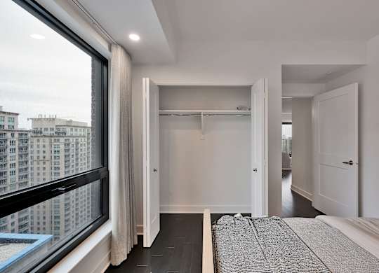 A bedroom with a large bed and a view of a cityscape through a window.