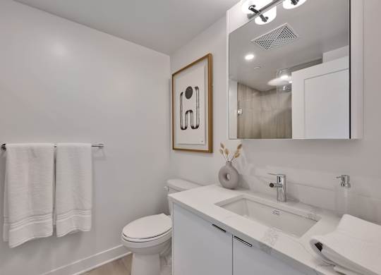 A white bathroom with a toilet, sink, and towel rack.