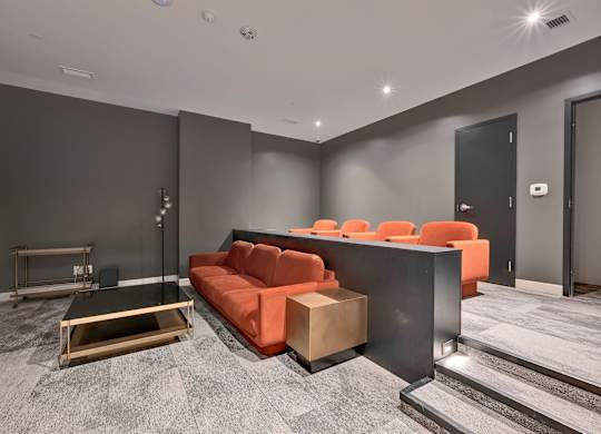 A modern living room with a grey carpet and a black sofa.