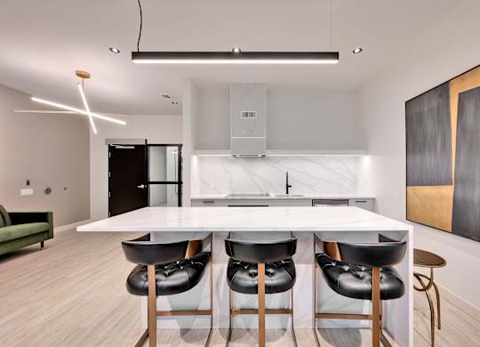 A modern kitchen with a white table and black barstools.