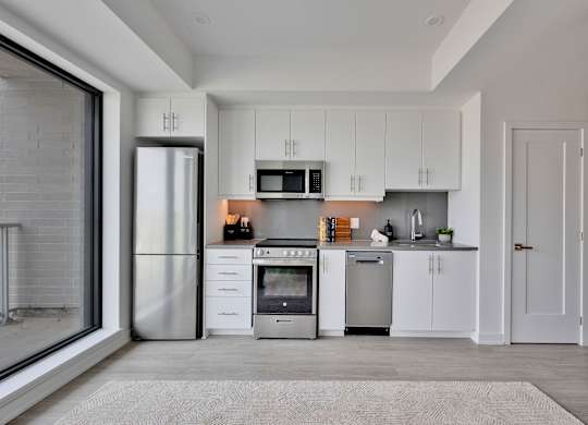 A modern kitchen with white cabinets and stainless steel appliances.