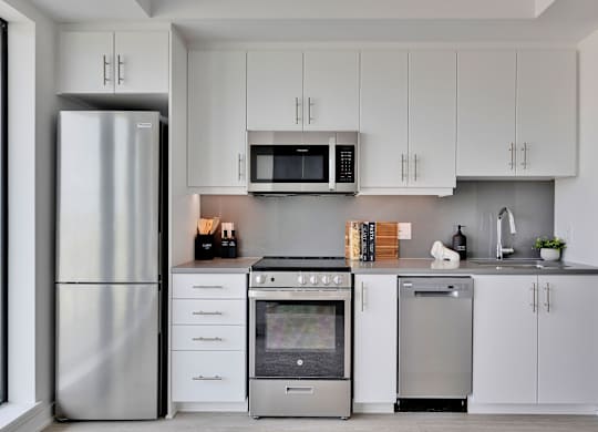 A modern kitchen with a stainless steel refrigerator, microwave, oven, and dishwasher.