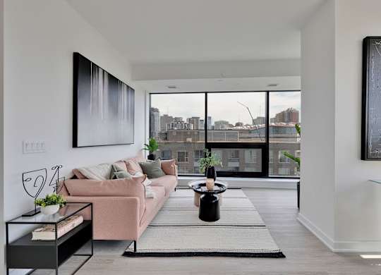 A modern living room with a pink couch and a large window overlooking the city.