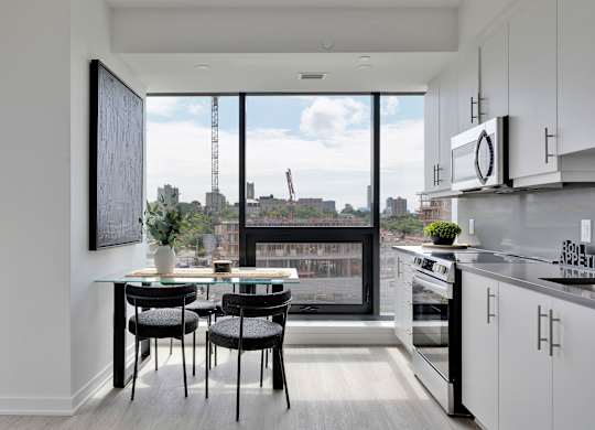 A modern kitchen with a table and chairs in front of a large window.