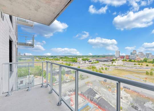 A balcony overlooks a construction site with a city skyline in the distance.