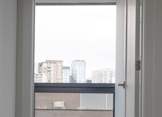 A bedroom with a bed and a view of the city.