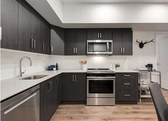 A modern kitchen with dark wood cabinets and stainless steel appliances.