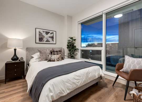 A bedroom with a large bed and a view of the city through the window.