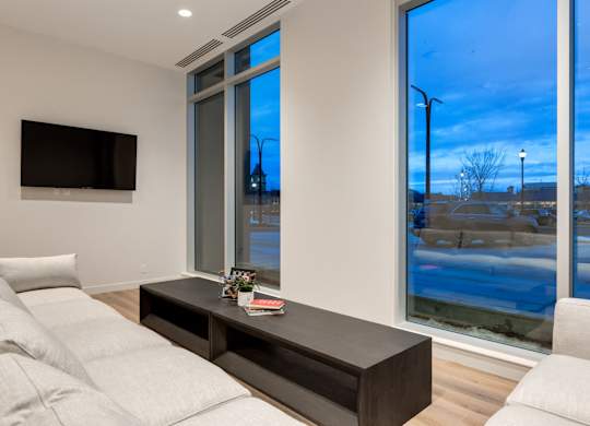 A modern living room with a large window and a flat screen TV mounted on the wall.