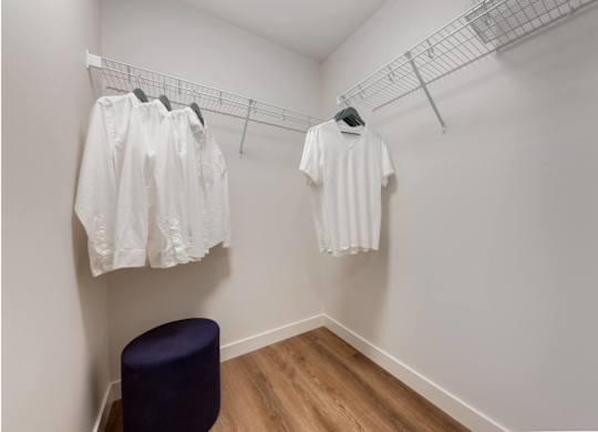 A row of white shirts hanging on a rack in a room.