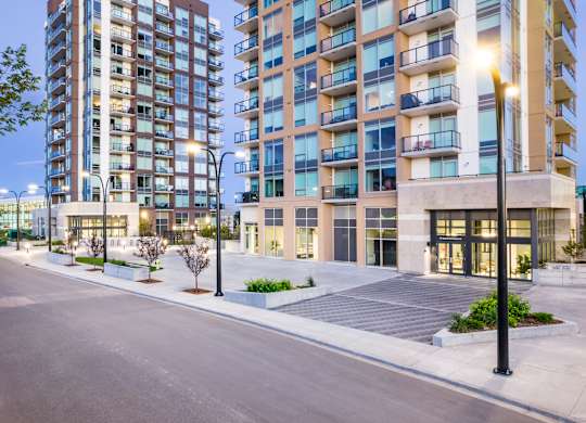 A modern apartment building with a well-maintained courtyard in front.