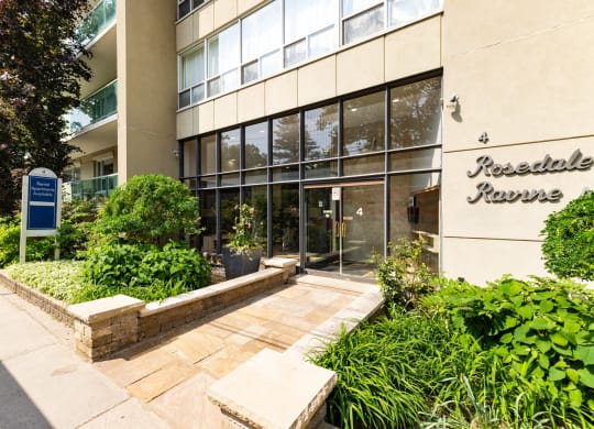 an office building with a walkway and plants in front of it