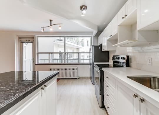 a kitchen with white cabinets and black counter tops