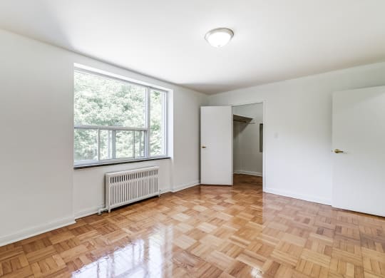 an empty living room with a large window and wooden floors