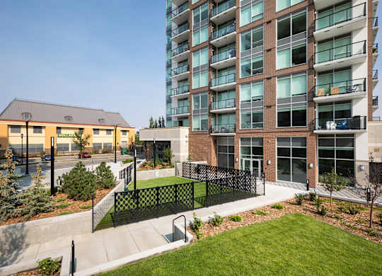 A modern building with a black fence and a green lawn in front.
