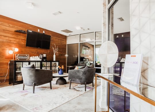 a living room with chairs and a table and a tv on the wall at Canalside, Augusta, GA