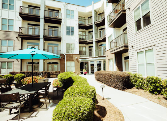 a patio with tables and umbrellas in front of an apartment building at Canalside, Augusta, GA