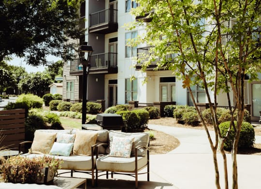 a patio with furniture and trees in front of an apartment building at Canalside, Augusta, GA