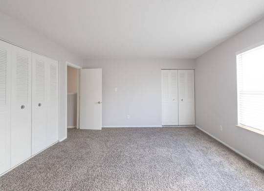 A room with white cupboards and a grey carpet.