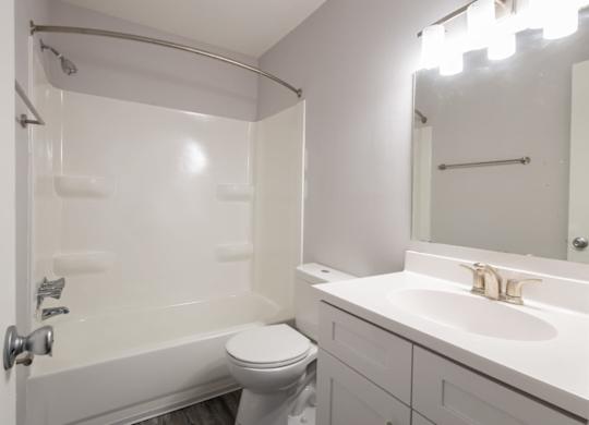A white bathroom with a toilet, sink, and bathtub.