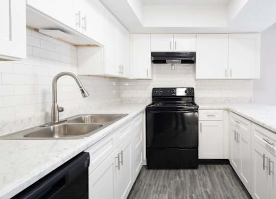 A black dishwasher is in a white kitchen.