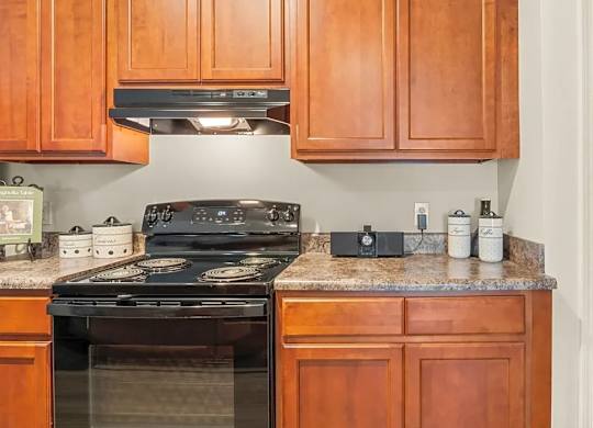 A kitchen with wooden cabinets and a black stove top.