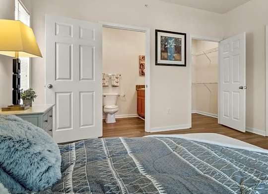 A bedroom with a blue bedspread and a painting on the wall.