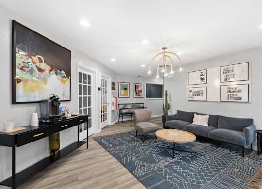 A living room with a grey couch, a coffee table, a side table, and a painting on the wall.