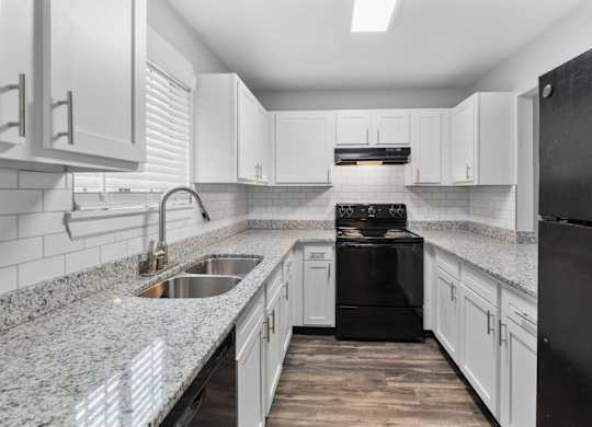 A modern kitchen with black appliances and white cabinets.