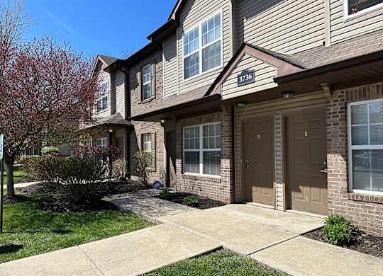 Townhome exterior with brick facade and garage doors at Northampton Village Apartments, Indianapolis, 46226