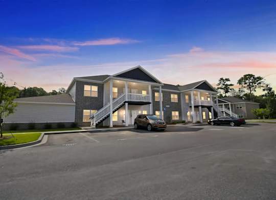 A modern two-story building with a parking lot in front.