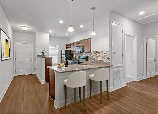 A kitchen with a bar and two chairs.