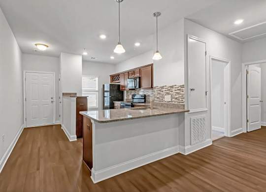 A kitchen with a white counter and wooden floors.