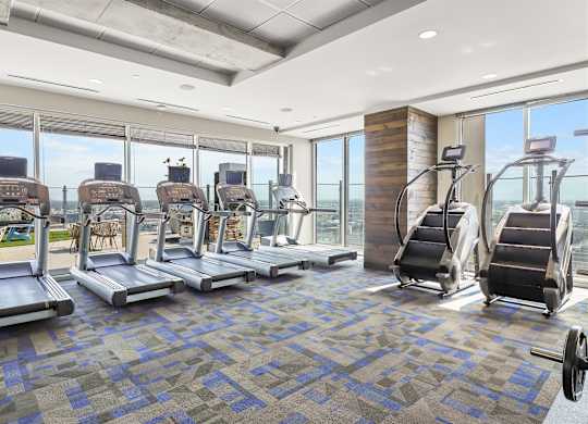 A gym with treadmills, elliptical machines, and a weight rack.