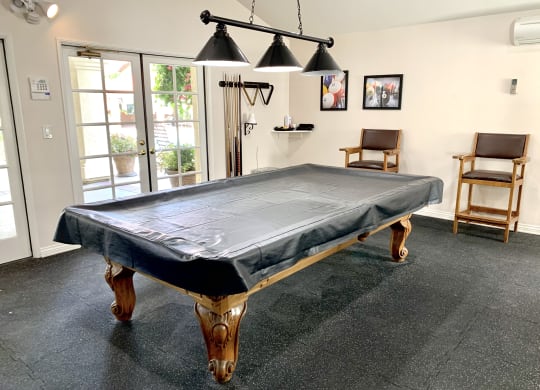 a pool table with a black cloth on it in a room with two chairs and