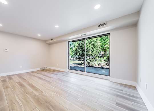A room with a large window and wooden flooring.