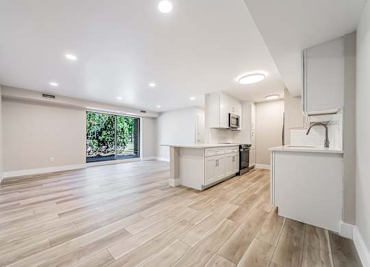 A spacious kitchen with wooden flooring and white cabinetry.