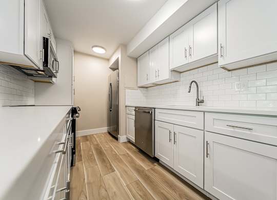 A kitchen with white cabinets and a wooden floor.