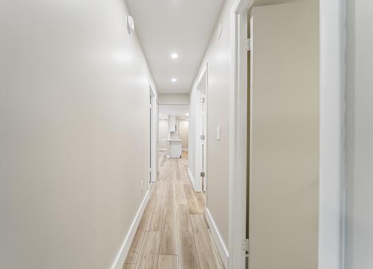 A long hallway with white walls and wood floors.