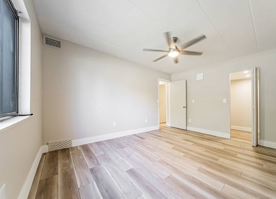 A room with a ceiling fan and wooden flooring.
