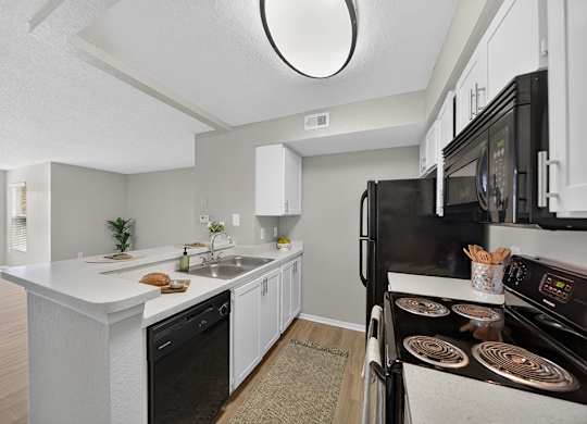 A modern kitchen with black appliances and white cabinetry.