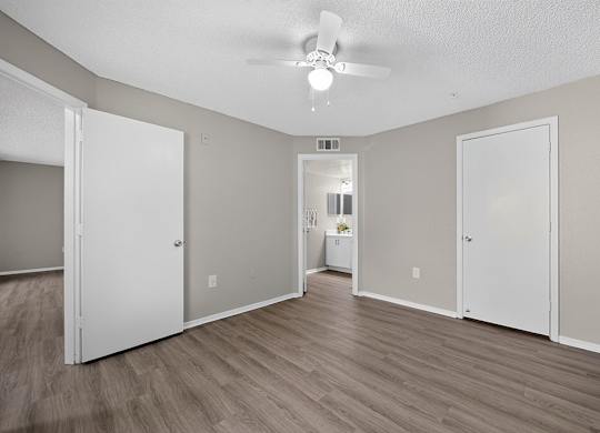 A room with a ceiling fan and light, and a door on the left.