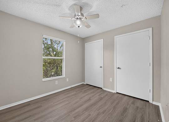 A room with a ceiling fan and a window with blinds.