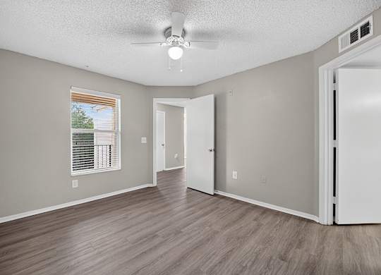 A room with a ceiling fan and a window with blinds.