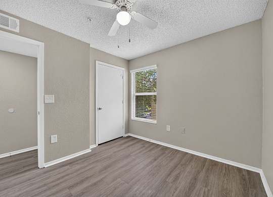 A room with a ceiling fan and a window with blinds.