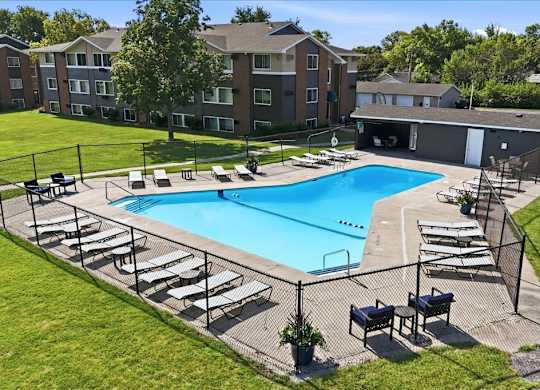 A swimming pool surrounded by sun loungers and a fence.